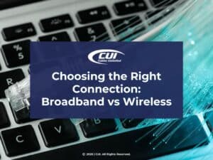 Featured: Close-up of keyboard with network cables plugged into port- Choosing the Right Connection: Broadband vs. Wireless.